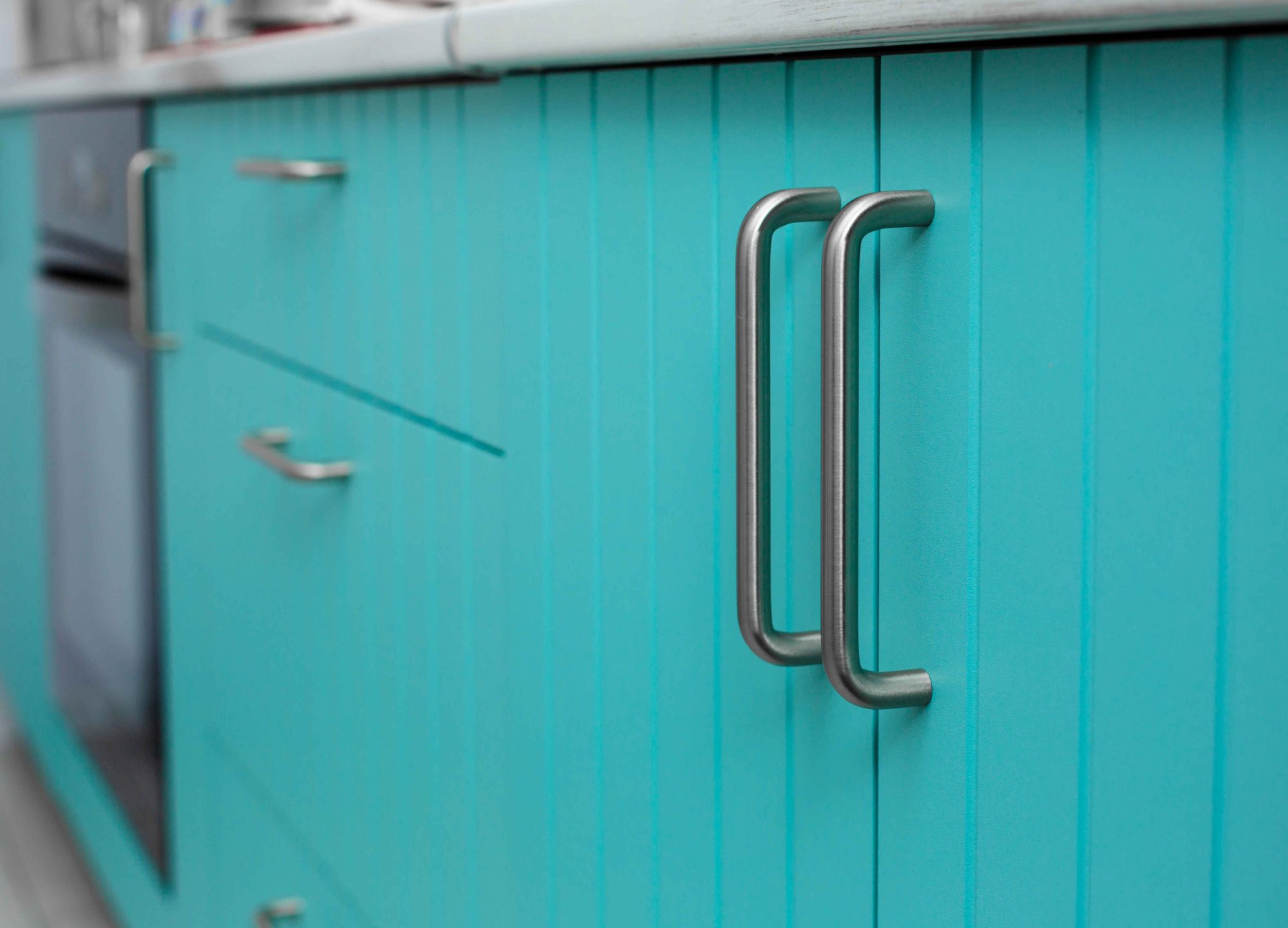 Blue wooden facade of kitchen cabinets made of thin strips with chrome handles